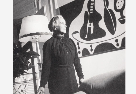 Eugenia Errazuriz at home in front of a painting by Picasso . Behind her a lamp designed by Alberto Giacometti for Jean Michel Frank.