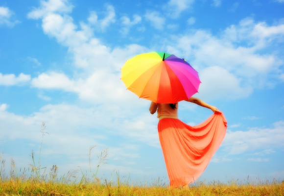 Mujer en campo con paraguas de colores